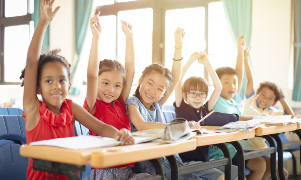 kids raising their hands to participate in a classroom