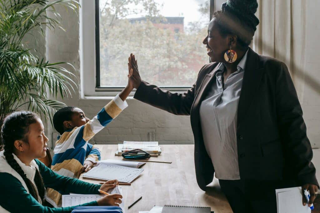 teacher high-fiving student in the classroom