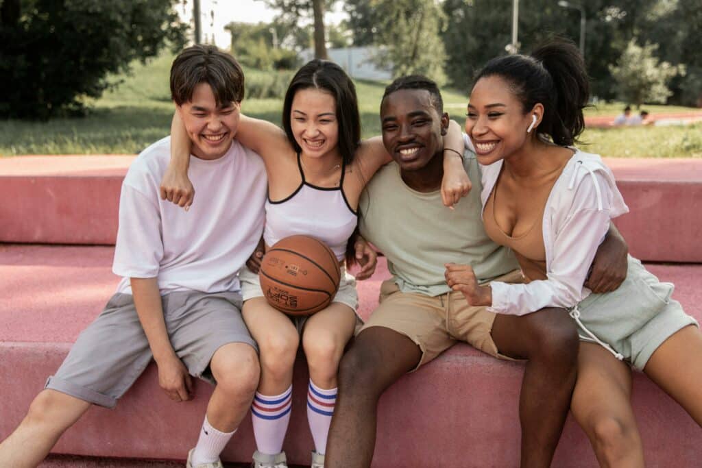 group of teens, boys and girls, hanging out on basketball court