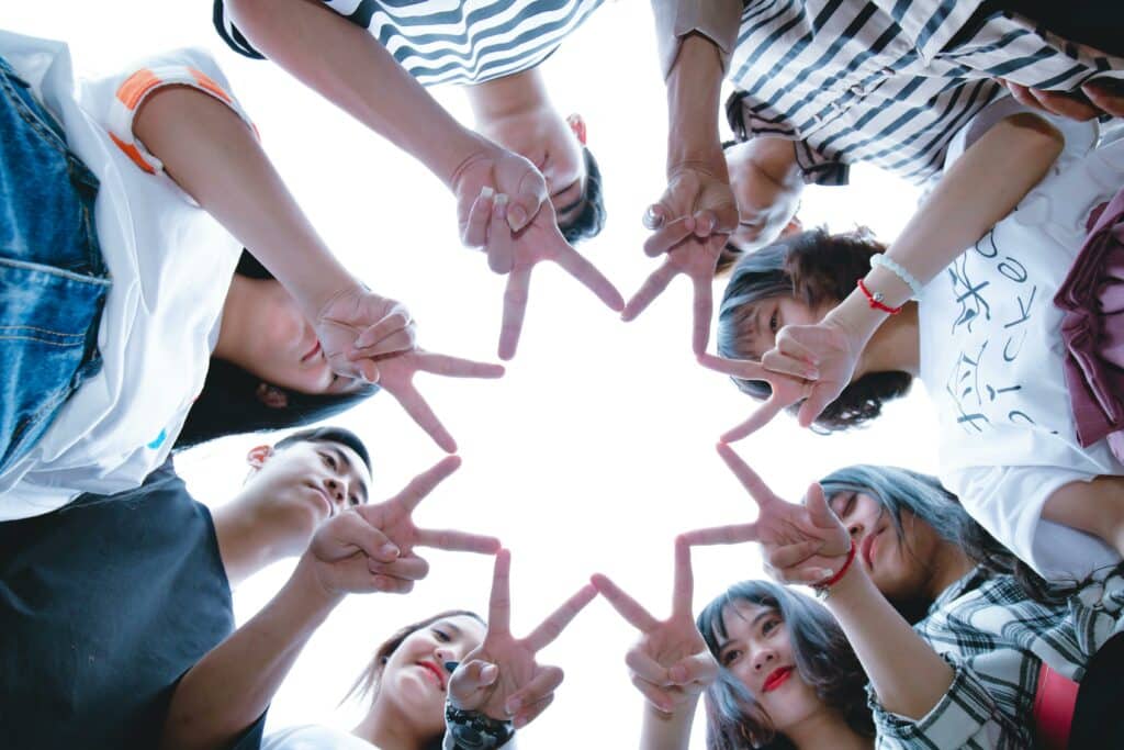 group of students in a circle, making a star with their fingers