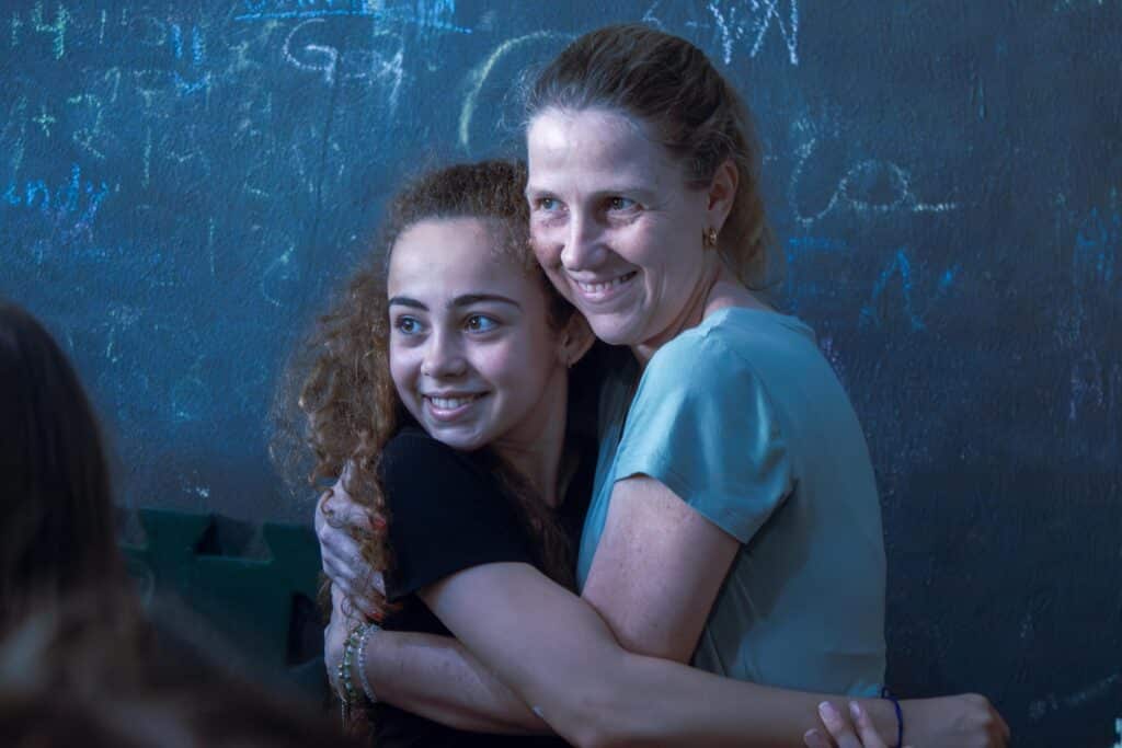 teacher hugging her student in a classroom