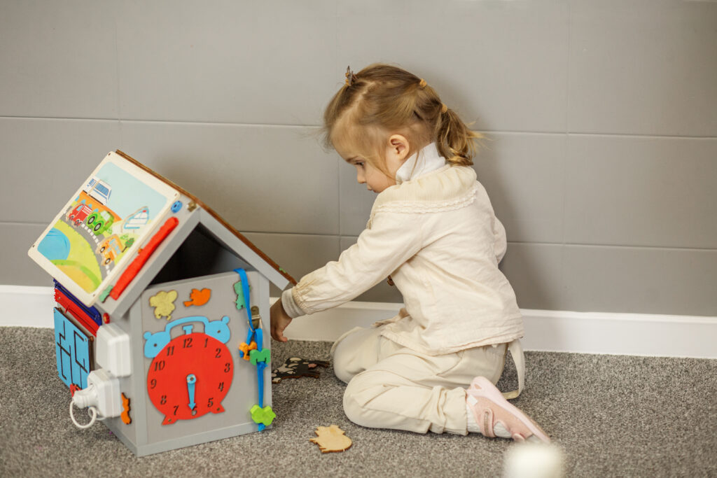 little girl playing with dollhouse